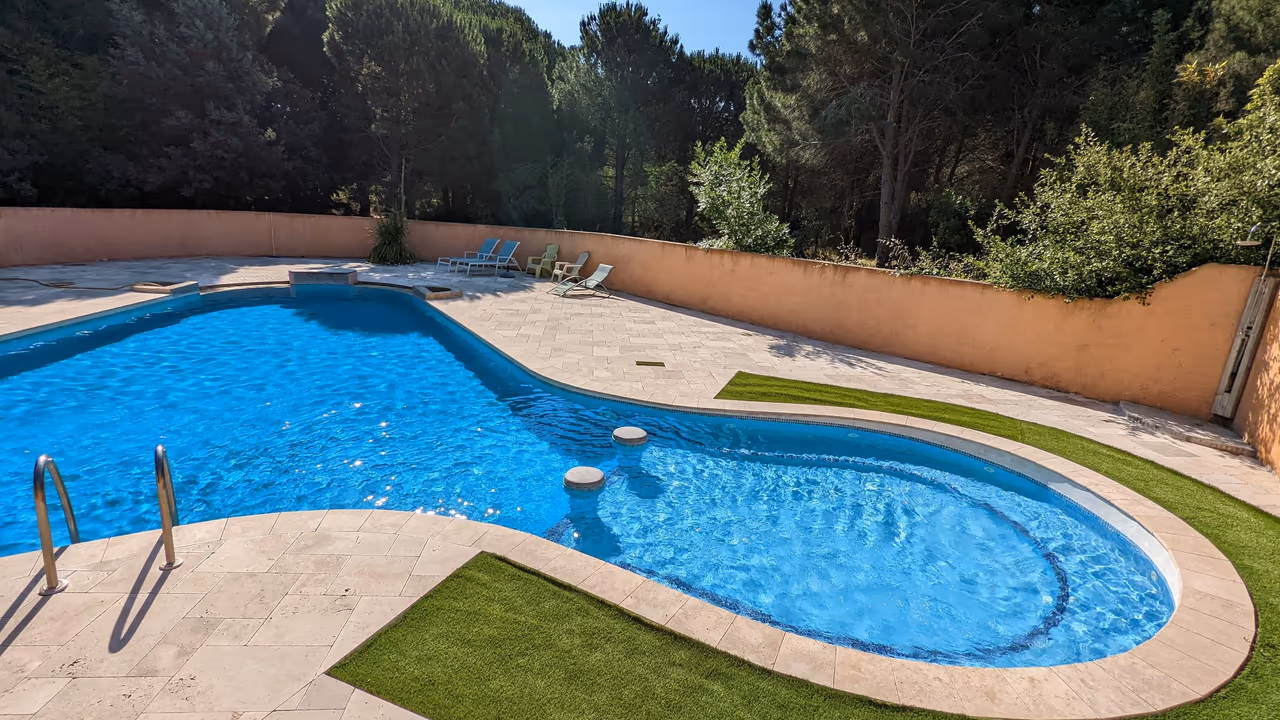 Piscine commune chauffée du domaine Allocigale, bordée de pins et de pelouse